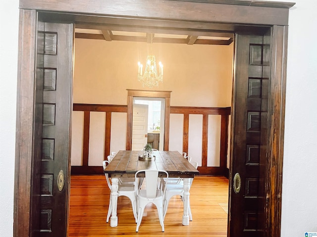 dining area featuring beamed ceiling, a chandelier, and hardwood / wood-style flooring