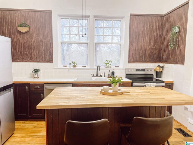 kitchen with decorative backsplash, light wood-type flooring, sink, and appliances with stainless steel finishes