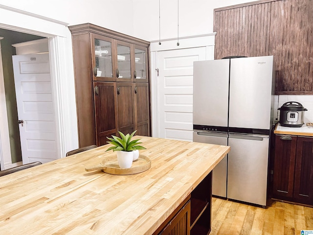 kitchen featuring dark brown cabinets, light hardwood / wood-style floors, and stainless steel refrigerator