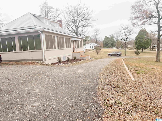 view of side of home with a lawn and a sunroom