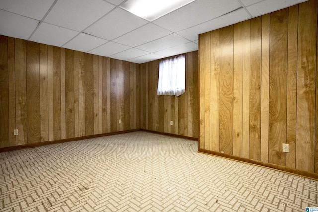 empty room with a paneled ceiling and wooden walls