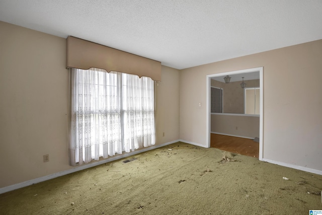 carpeted empty room featuring a textured ceiling