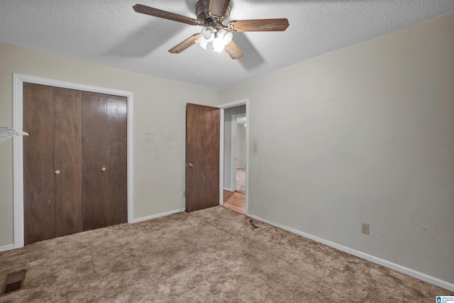 unfurnished bedroom featuring ceiling fan, light colored carpet, a textured ceiling, and a closet