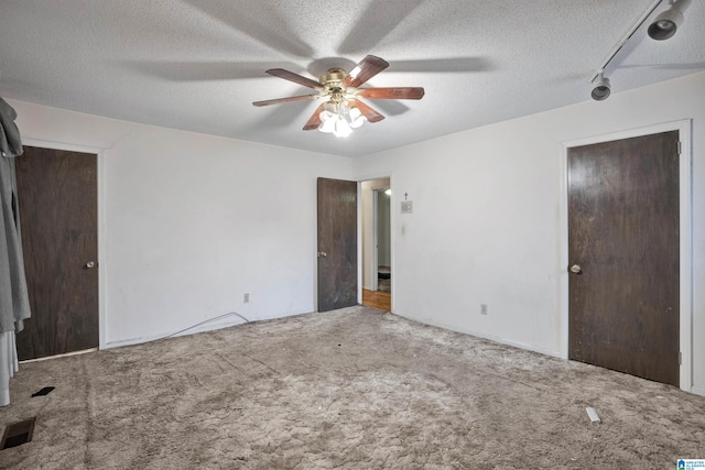 unfurnished bedroom with carpet flooring, a textured ceiling, and ceiling fan