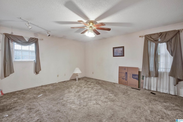 unfurnished room with carpet flooring, a textured ceiling, and track lighting