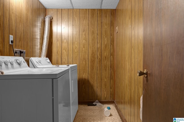 clothes washing area with wooden walls and washer and clothes dryer