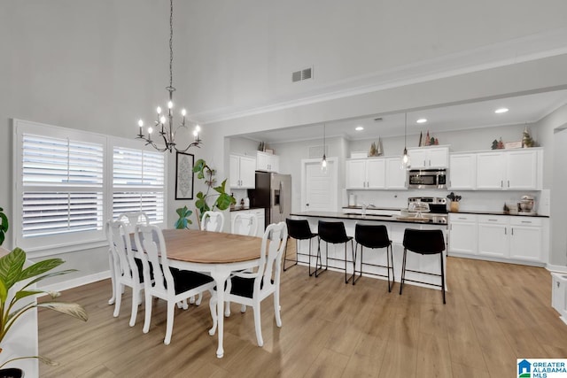 dining room with crown molding, sink, an inviting chandelier, and light wood-type flooring