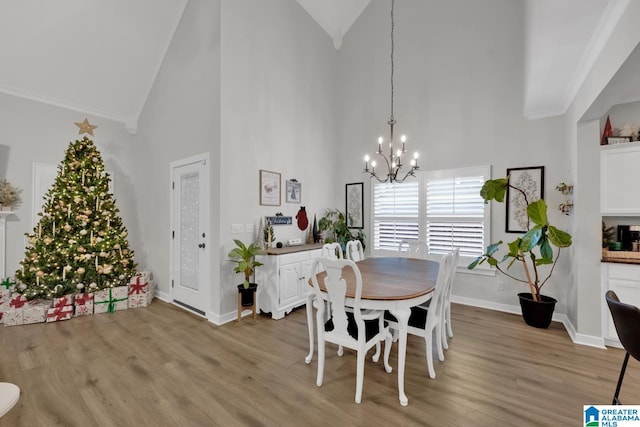 dining area featuring light wood-type flooring, crown molding, high vaulted ceiling, and an inviting chandelier