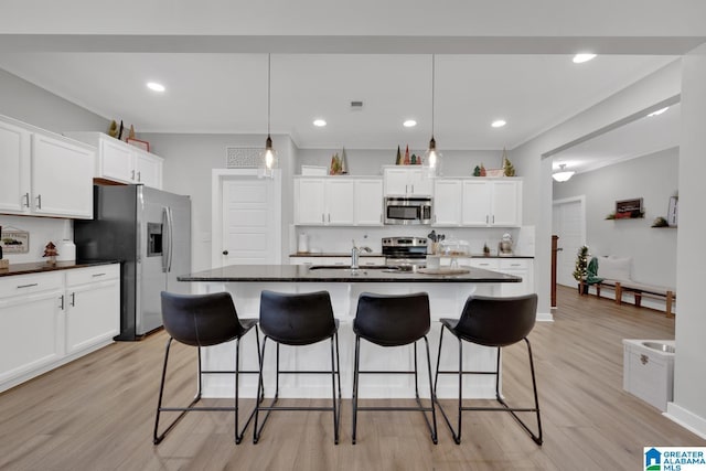 kitchen featuring a center island with sink, light hardwood / wood-style floors, white cabinetry, and stainless steel appliances