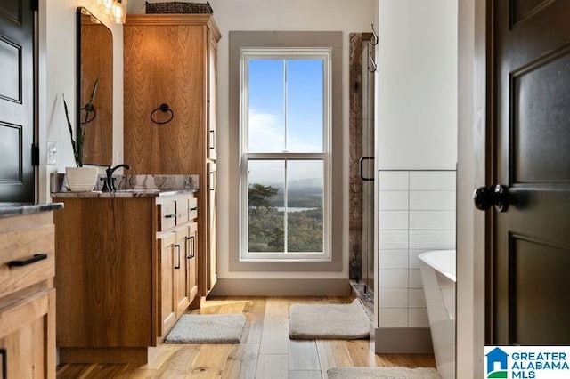 bathroom featuring vanity, wood-type flooring, tile walls, and independent shower and bath