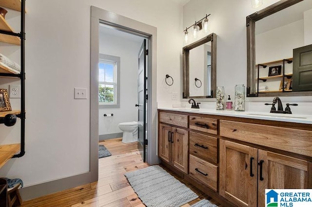 bathroom with hardwood / wood-style floors, vanity, and toilet