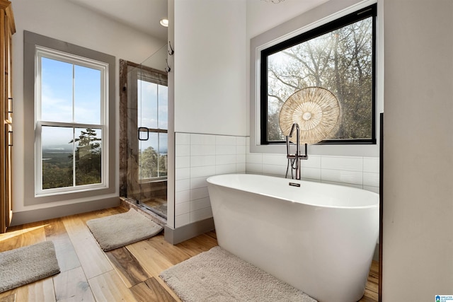 bathroom featuring a bathing tub, tile walls, and hardwood / wood-style flooring