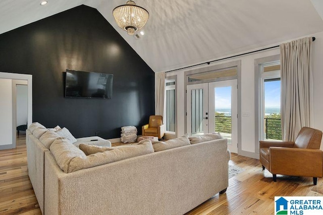 living room featuring light hardwood / wood-style flooring, high vaulted ceiling, and a chandelier