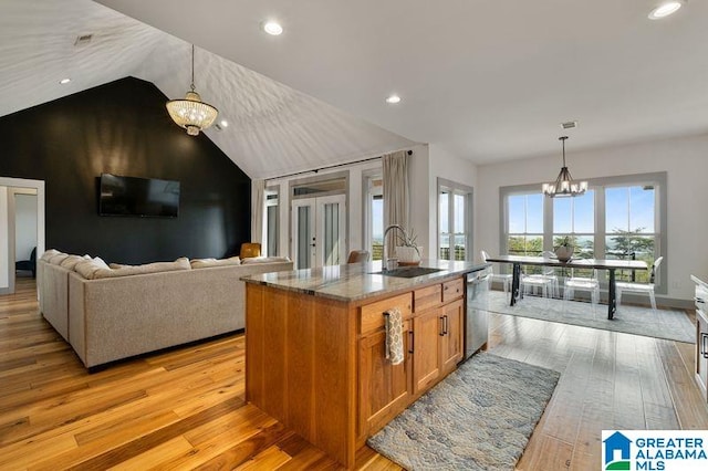 kitchen featuring a kitchen island with sink, light hardwood / wood-style flooring, vaulted ceiling, and an inviting chandelier