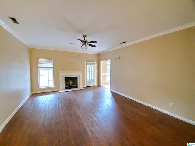 unfurnished living room with plenty of natural light, ceiling fan, crown molding, and dark wood-type flooring