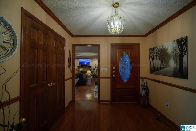 foyer featuring crown molding, dark hardwood / wood-style flooring, a textured ceiling, and an inviting chandelier