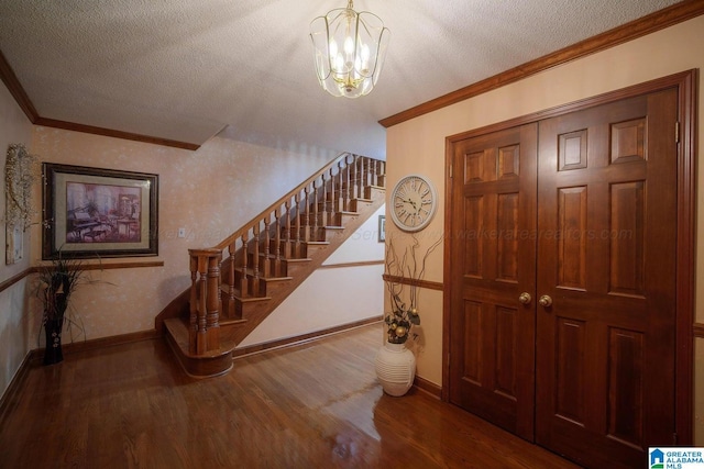 interior space featuring hardwood / wood-style floors, ornamental molding, a textured ceiling, and an inviting chandelier