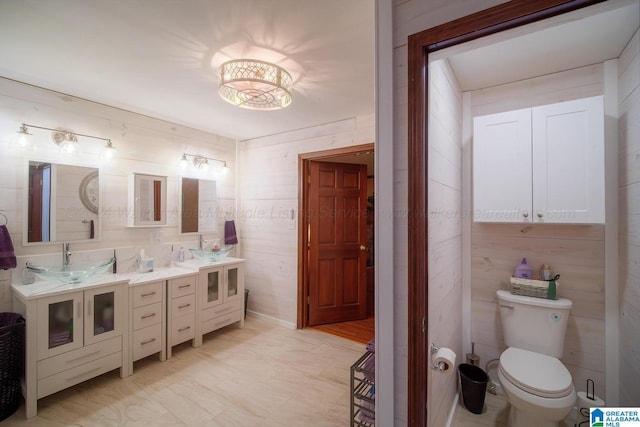 bathroom featuring vanity, toilet, and wood walls