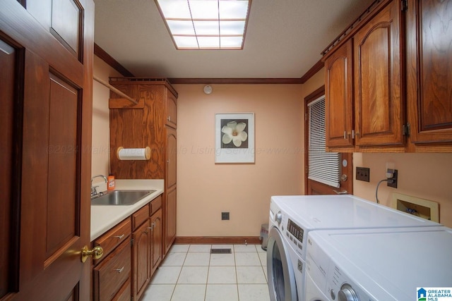 clothes washing area featuring cabinets, sink, crown molding, washing machine and dryer, and light tile patterned floors