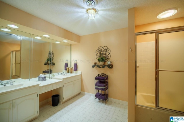 bathroom with vanity, bath / shower combo with glass door, and a textured ceiling