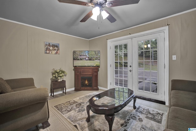 living room featuring ceiling fan, wood walls, ornamental molding, and french doors