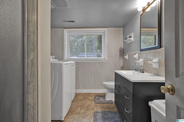 bathroom featuring tasteful backsplash, tile patterned floors, vanity, toilet, and wood walls