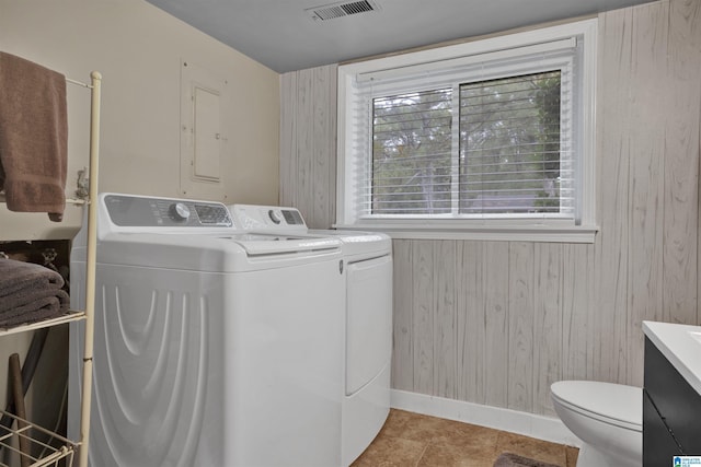 laundry room with light tile patterned floors, independent washer and dryer, and wooden walls