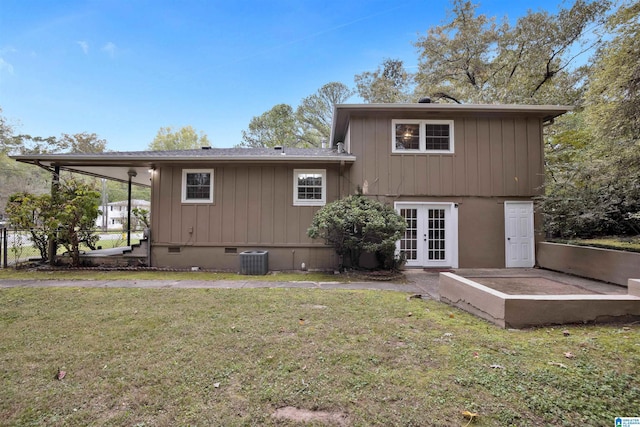 rear view of house featuring a lawn, central air condition unit, and french doors