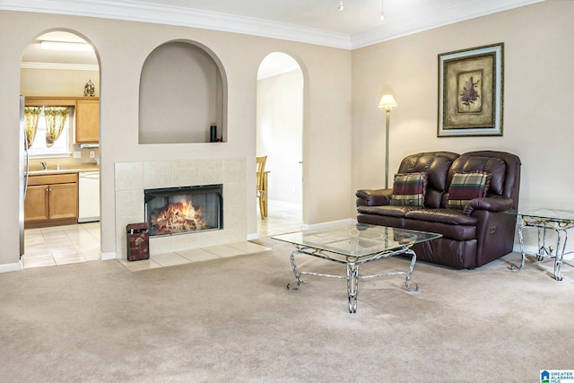 living room with light colored carpet, ornamental molding, sink, and a tiled fireplace