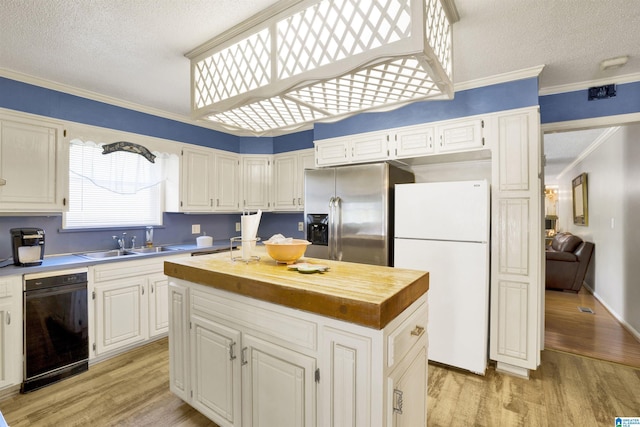 kitchen with sink, a center island, crown molding, white fridge, and light wood-type flooring