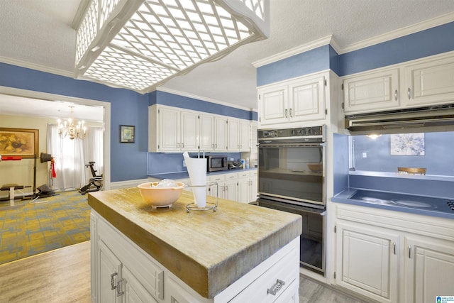 kitchen with white cabinets, ornamental molding, and light wood-type flooring