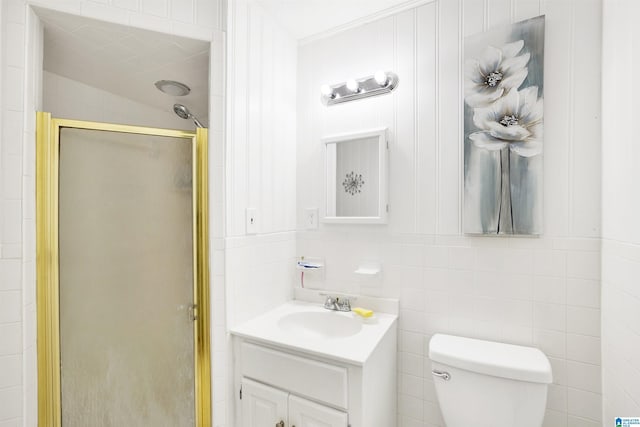 bathroom with vanity, toilet, an enclosed shower, and tile walls