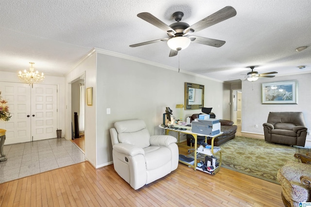 living room with ceiling fan with notable chandelier, a textured ceiling, light wood-type flooring, and ornamental molding