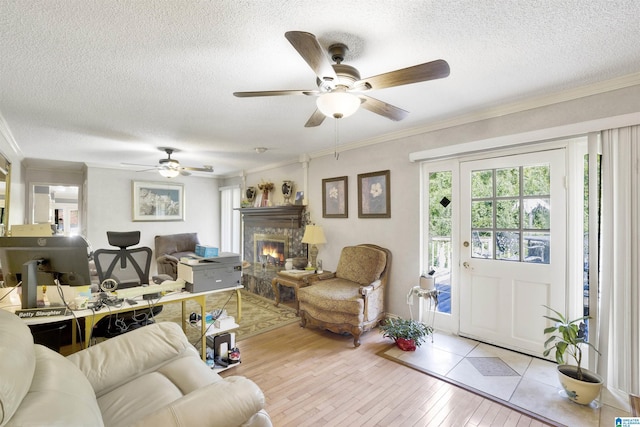 living room with crown molding, ceiling fan, a textured ceiling, and light wood-type flooring