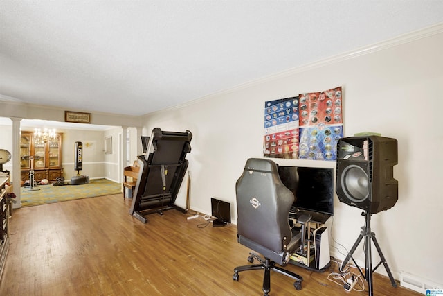 home office featuring hardwood / wood-style flooring, decorative columns, ornamental molding, and a chandelier