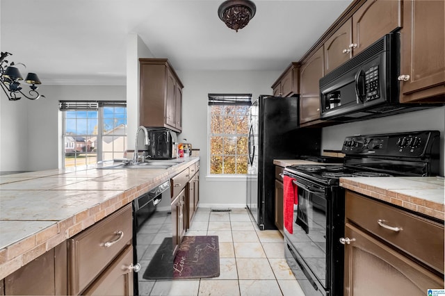 kitchen with dark brown cabinets, sink, black appliances, light tile patterned floors, and tile counters