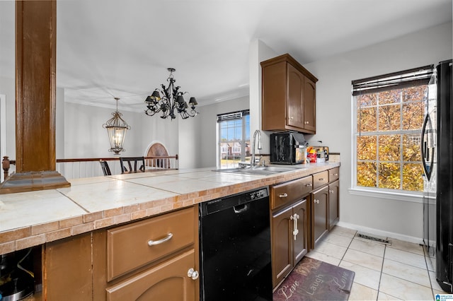 kitchen featuring sink, tile counters, hanging light fixtures, an inviting chandelier, and black appliances