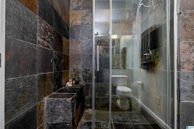 bathroom featuring a shower with shower door, tile walls, and toilet