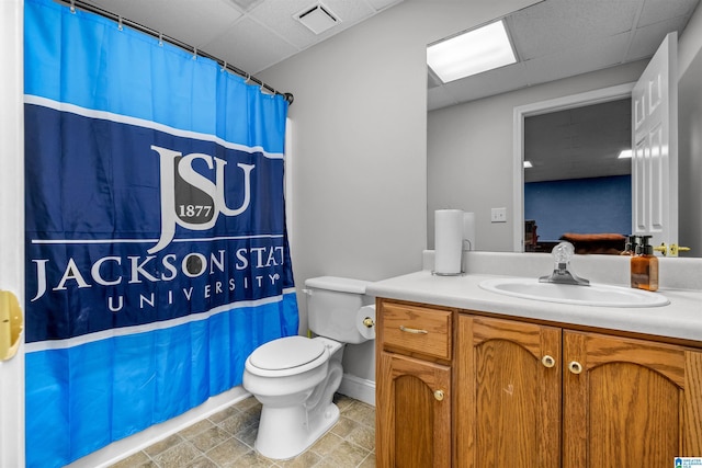 bathroom with curtained shower, a drop ceiling, vanity, and toilet