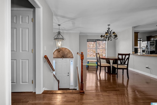 foyer entrance with a notable chandelier, crown molding, and dark wood-type flooring