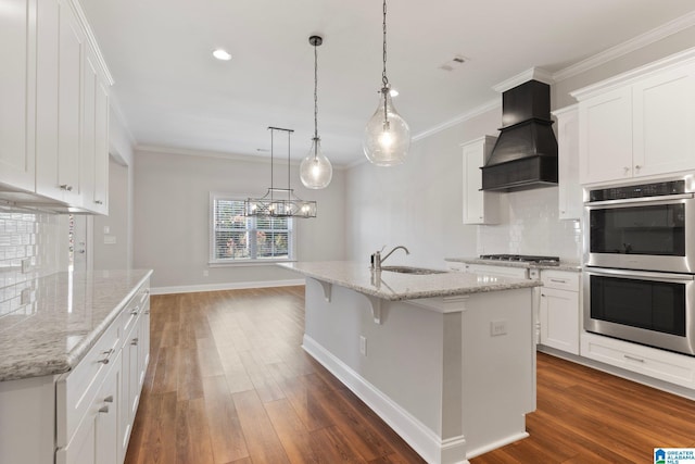 kitchen with white cabinetry, a center island with sink, stainless steel appliances, and custom range hood