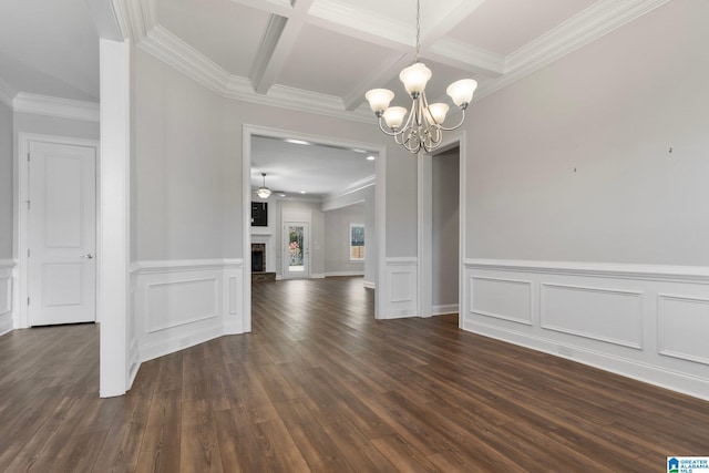 unfurnished dining area featuring dark wood-type flooring, coffered ceiling, beamed ceiling, crown molding, and ceiling fan with notable chandelier