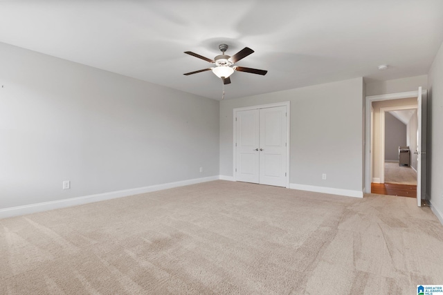 unfurnished bedroom with light carpet, a closet, and ceiling fan