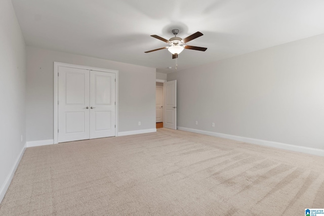 unfurnished bedroom featuring ceiling fan, light colored carpet, and a closet