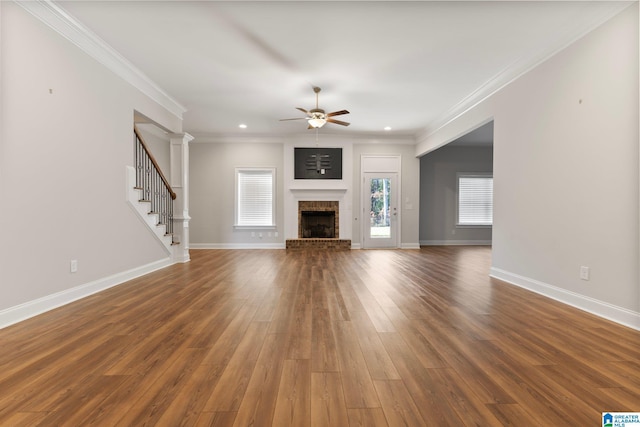 unfurnished living room with a fireplace, ceiling fan, crown molding, and dark wood-type flooring