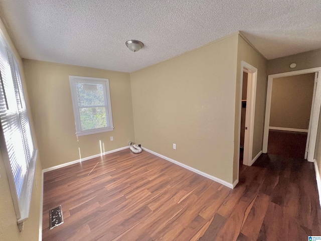 empty room featuring dark hardwood / wood-style floors and a textured ceiling