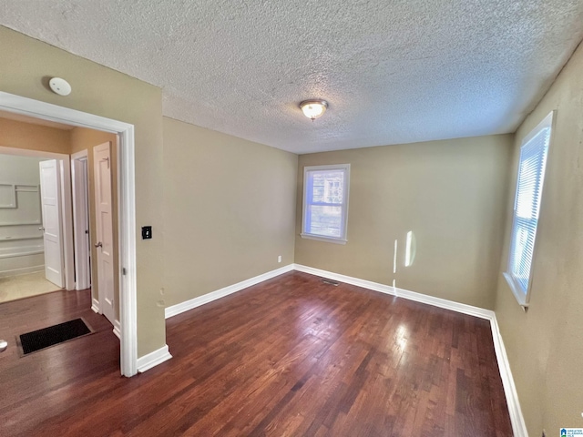 spare room featuring a textured ceiling and dark hardwood / wood-style floors