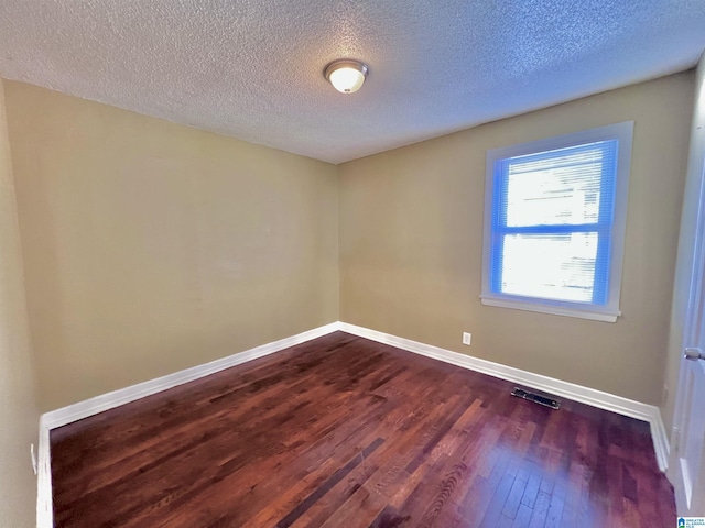 spare room featuring wood-type flooring and a textured ceiling