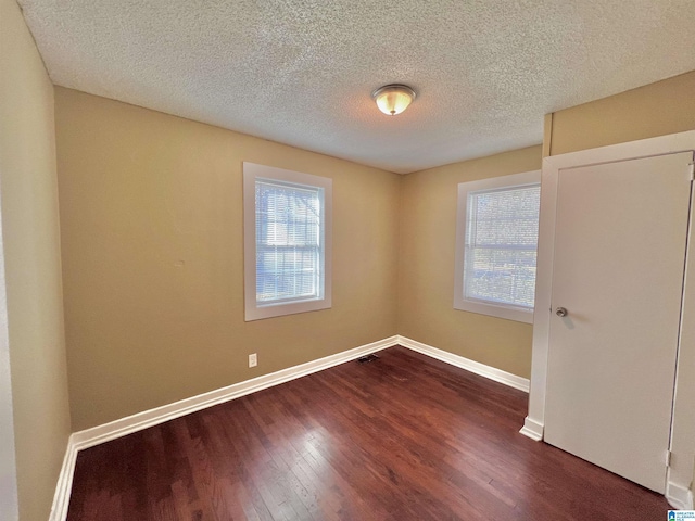 empty room featuring a textured ceiling and dark wood-type flooring