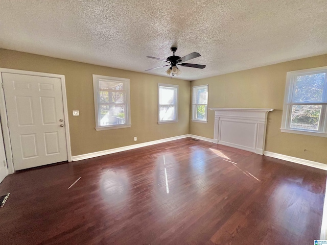 empty room with ceiling fan, dark wood-type flooring, and a textured ceiling